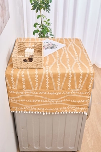 Detalle de la funda de refrigerador amarilla con estampado floral blanco y pompones