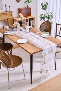 Detail of white lace table runner with colorful floral embroidery on a wooden table