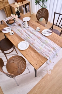 Detailed embroidery of colorful flowers on a sheer lace table runner for wedding decor