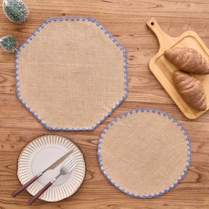 Detalle de manteles individuales de yute con encaje violeta en mesa de madera
