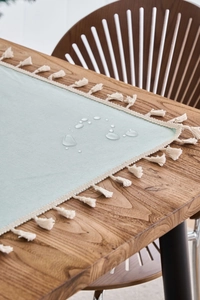 Detail of waterproof mint green tablecloth showing water droplets and white tassel edges