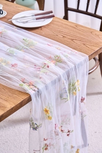 Detail of white lace table runner featuring colorful floral embroidery on mesh fabric