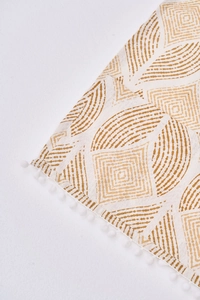 Détail de la housse anti-poussière à motifs géométriques et bordure à pompons blancs
