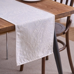 Elegant white paisley jacquard table runner on a wooden dining table in a home setting