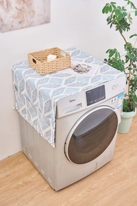 Vue détaillée de la housse anti-poussière géométrique bleue et blanche avec pompons blancs