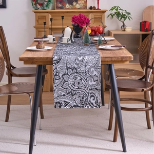 Elegant black and white paisley table runner displayed with tea set on wooden dining table