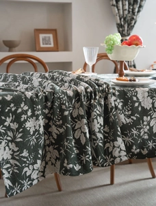 Détail montrant le drapé lourd et la texture jacquard florale de la nappe vert foncé
