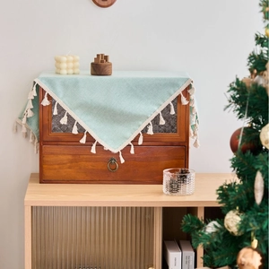 Mint green waterproof TPU tablecloth with white tassels on a vintage wooden cabinet