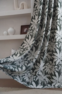 Close-up of tropical palm leaf pattern on dark green chenille fabric with natural drape