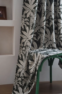 Close-up of dark green tropical leaf jacquard on chenille fabric draped on a chair