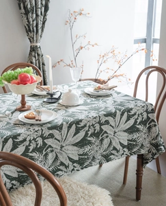 Detail of vintage dark green tablecloth featuring large white tropical leaf jacquard patterns