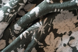 Vue macro détaillée du tissu jacquard vert foncé avec des motifs floraux blancs et texture