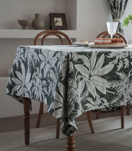 Detailed texture of dark green jacquard tablecloth with tropical white leaf patterns