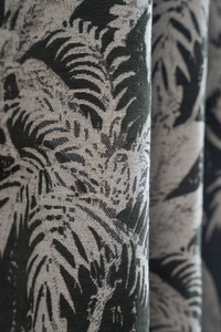 Detail showing high-density jacquard weave of dark green tropical palm leaves on curtains