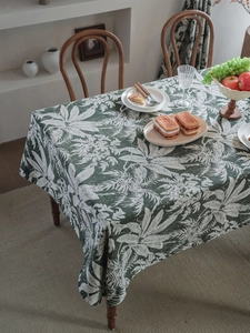 Detailed macro shot of dark green jacquard tablecloth with white tropical leaf patterns