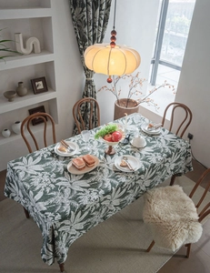 Detail view of dark green tablecloth with white tropical leaf prints and cotton linen texture