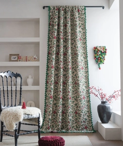 Detail of Christmas holly berry printed curtain with green fringe tassels and festive decor