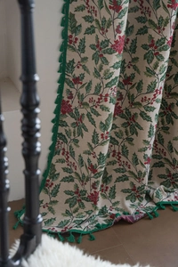Detailed weave of Christmas holly curtain with green tassel trim and festive berry patterns