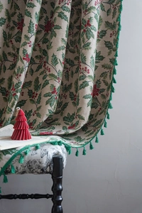 Detailed view of Christmas holly berry printed fabric with decorative green tassels