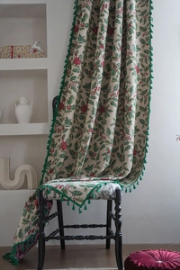 Close-up of Christmas holly leaf pattern curtain with green tassel edge on a wooden chair