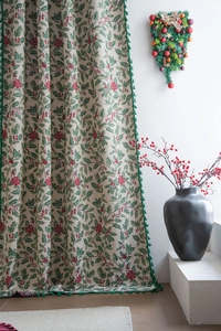 Close-up of Christmas holly leaf print on fabric with decorative green fringe edge