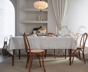 Close-up of white 3D floral jacquard tablecloth with elegant dark brown wavy hem trim