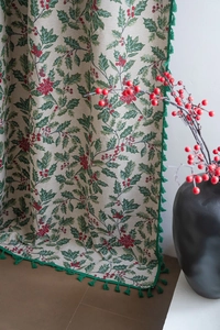 Close-up of jacquard fabric with Christmas holly patterns and green tassel edge trim