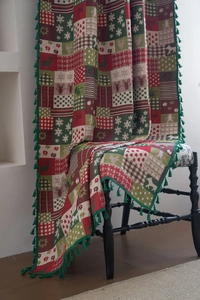 Detailed texture of Christmas tapestry throw with reindeer patterns and green fringe