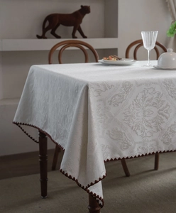 Close-up of white jacquard tablecloth with elegant floral patterns and dark lace trim