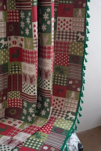 Detailed knit texture of Christmas curtain with reindeer patterns and green tassels