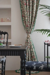 Detail of Christmas holly berry curtain with green tassels and wooden deer tieback