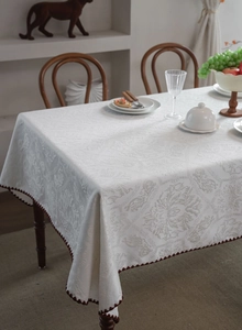 Close-up of white damascus jacquard tablecloth with brown wavy edge detail and rich texture
