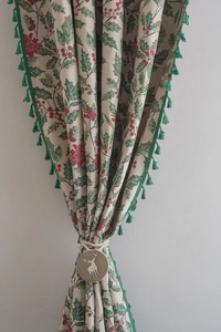 Close-up of Christmas holly jacquard curtain with green fringe and reindeer buckle