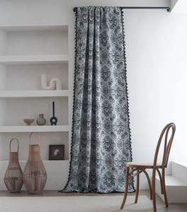 Close-up of black damask patterned curtain with elegant tassel trim in a vintage interior