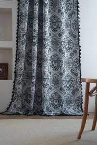 Close-up of retro black jacquard floral pattern on white curtain fabric with tassel fringe