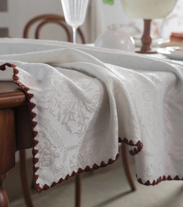 Close-up of white jacquard tablecloth with elegant brown scalloped crochet lace edges