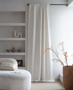Detail of off-white jacquard curtain featuring delicate fringe trim and textured fabric