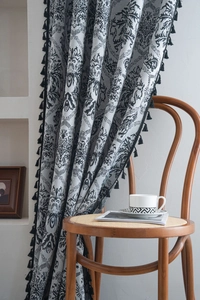 Close-up of vintage grey curtain featuring black floral jacquard patterns and decorative tassels