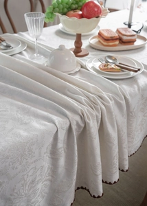 Macro shot of white jacquard tablecloth texture with red scalloped edge detail