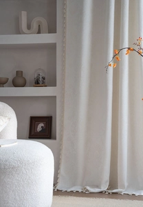 Close-up of cream jacquard floral relief curtain fabric with elegant tassel trim details