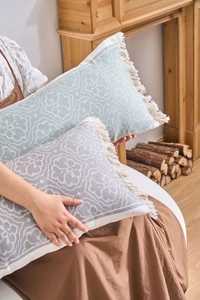 Dettaglio dei cuscini lombari jacquard con motivi floreali e bordi con frange fini