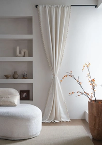 Detailed view of cream-white curtains with embossed jacquard patterns and elegant tassels