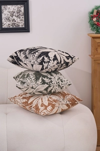 Detail of three textured chenille throw pillows with tropical palm leaf patterns on sofa