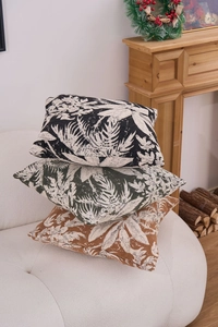 Three jacquard chenille throw pillows with leaf patterns on a white sofa in a living room