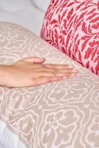 Dettaglio di cuscini lombari jacquard con trame damascate in beige e rosso morbido