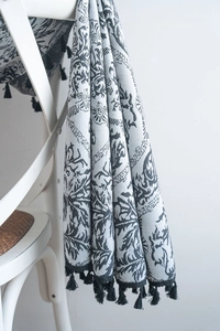 Close-up of bohemian floral printed textile with elegant black fringe tassels on a chair