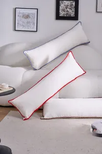 Detail of cream rectangular bolster pillow with colorful crochet edges on a white sofa