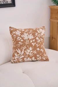 Close-up of caramel chenille jacquard pillow with white floral pattern on a white sofa
