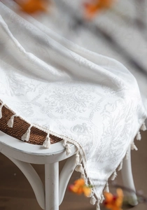 Close-up of cream white damask jacquard fabric with elegant fringe tassels and texture