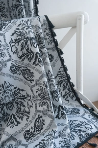 Detail of vintage floral jacquard fabric with black embossed patterns and tassel fringe